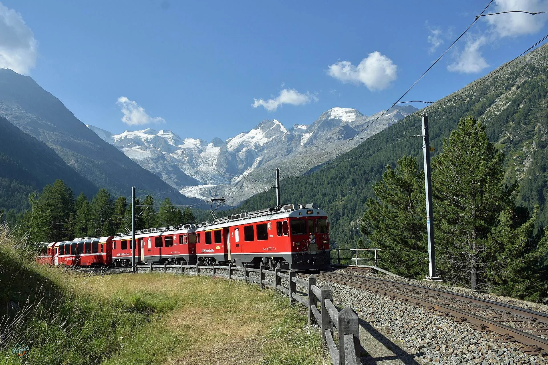 A red Bernina line train curving through the Morteratsch area with the glacier and snowy peaks behind.