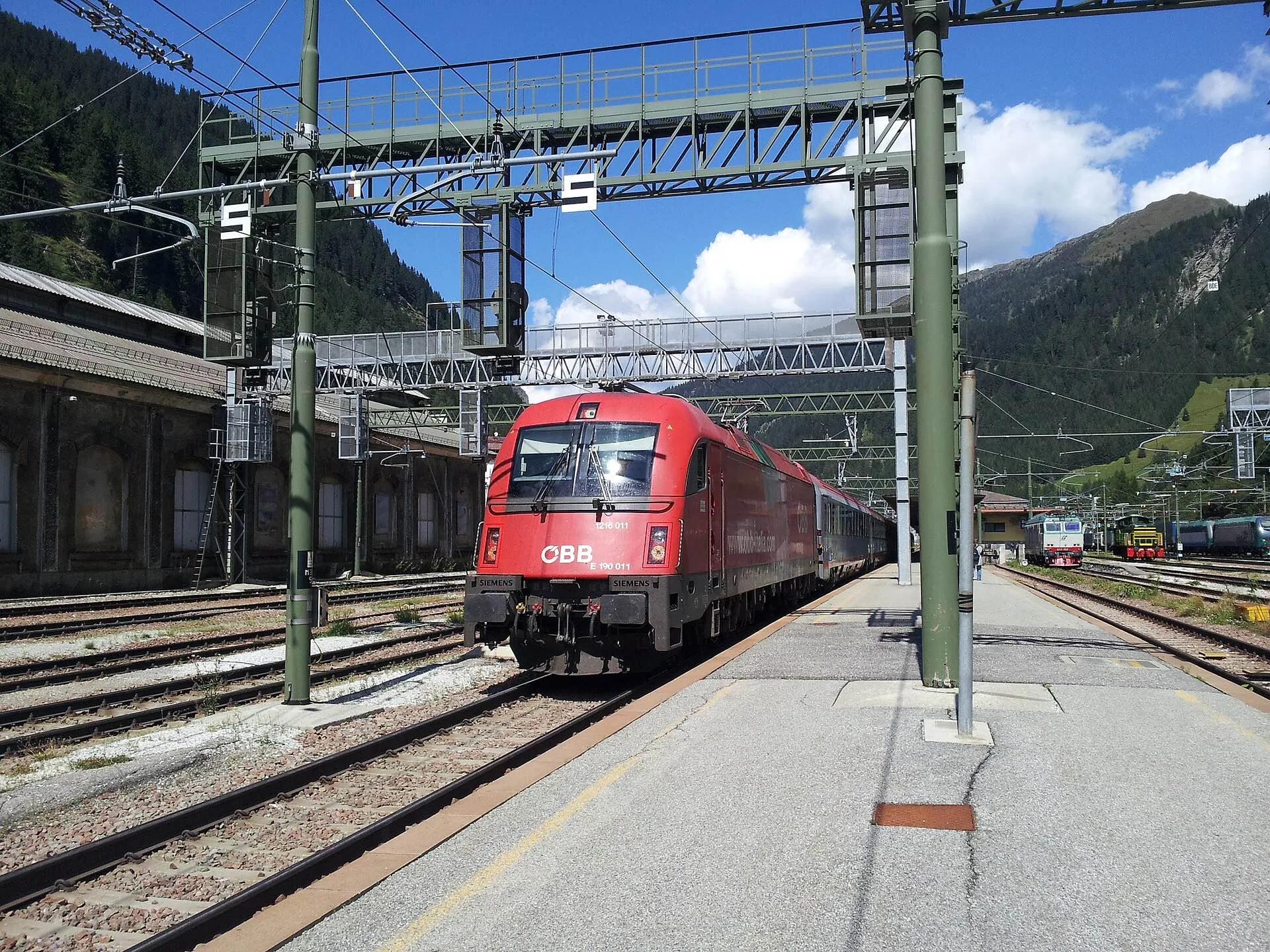 A red ÖBB locomotive with a Eurocity train at the platforms of Brenner station on the pass.