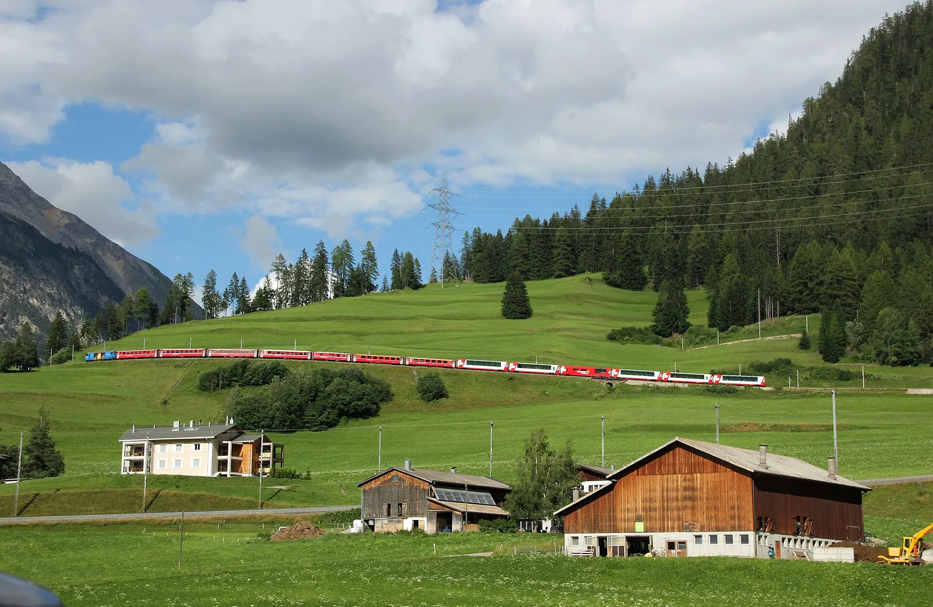 The Glacier Express climbing through green meadows near Bergün on the Albula line.