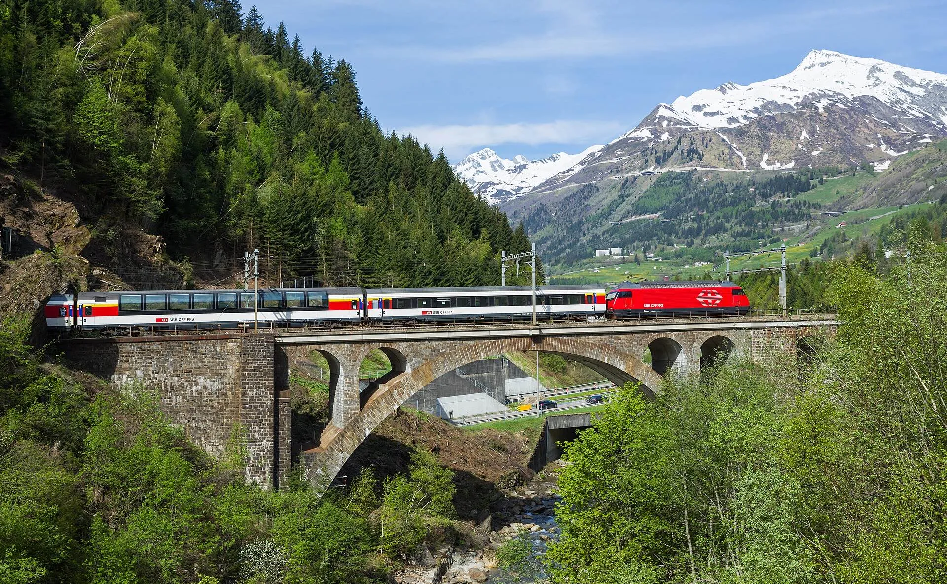 An SBB locomotive with an intercity train on a stone arch bridge between Ambrì-Piotta and Airolo.