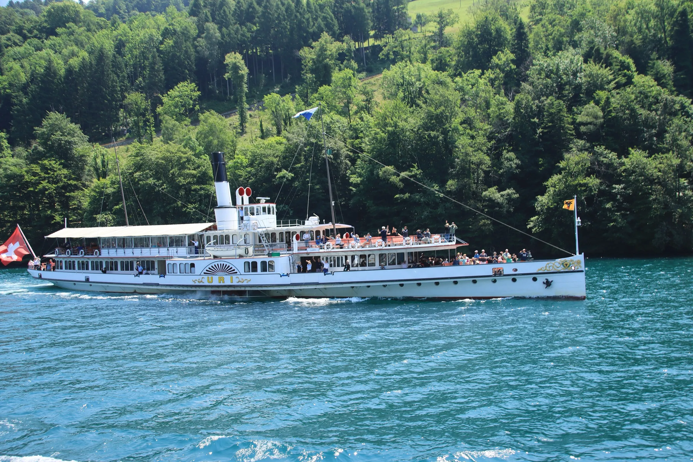 The paddle steamer Uri on Lake Lucerne near Treib with wooded shores behind.