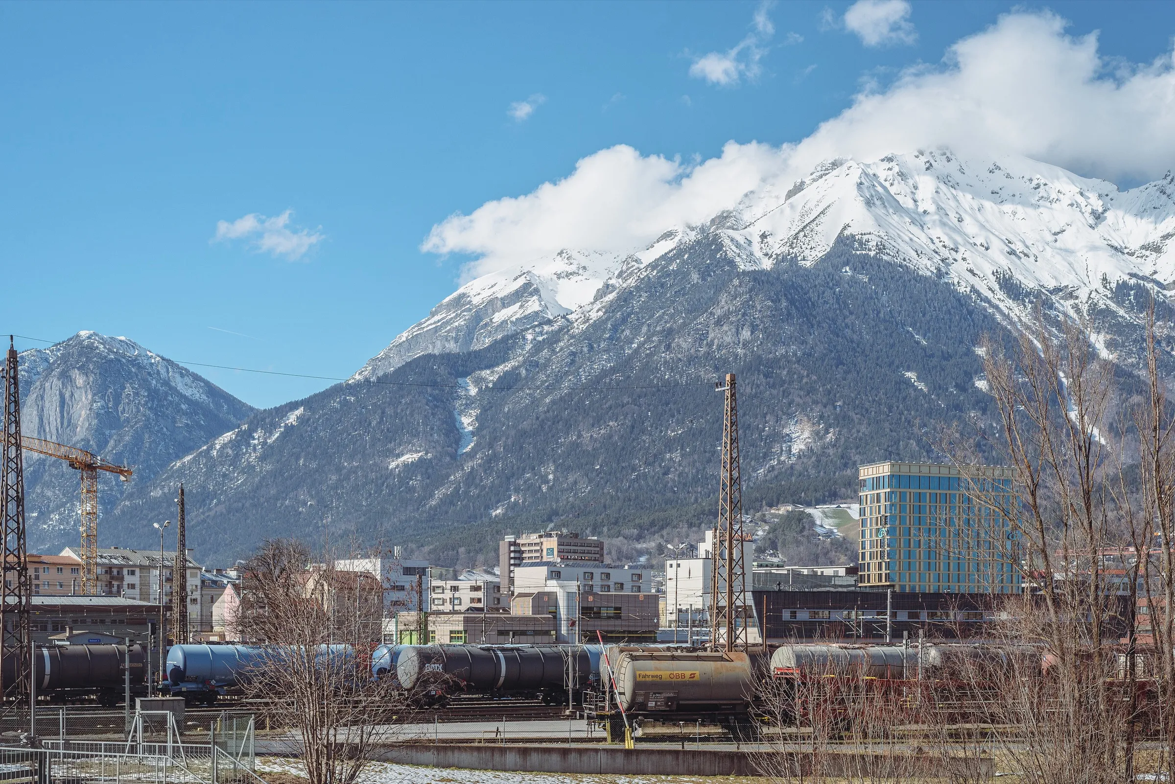 Snow-covered Nordkette mountains rising above the tracks and city blocks south of Innsbruck Hauptbahnhof.