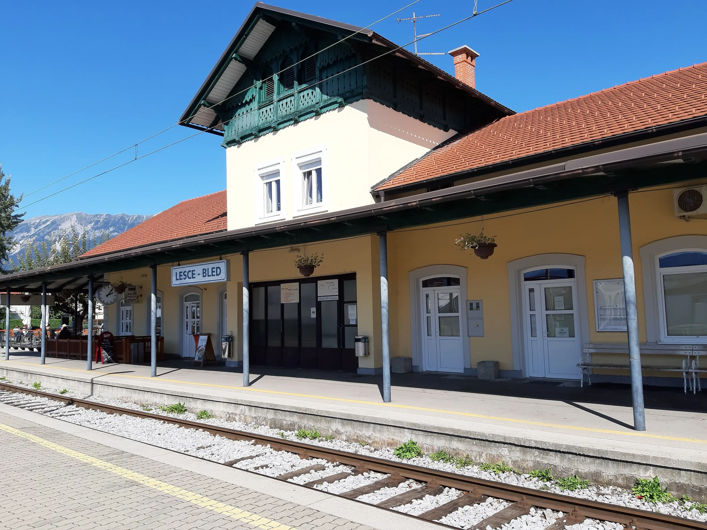 The yellow station building of Lesce-Bled with its wooden gable and the Karavanke mountains behind.