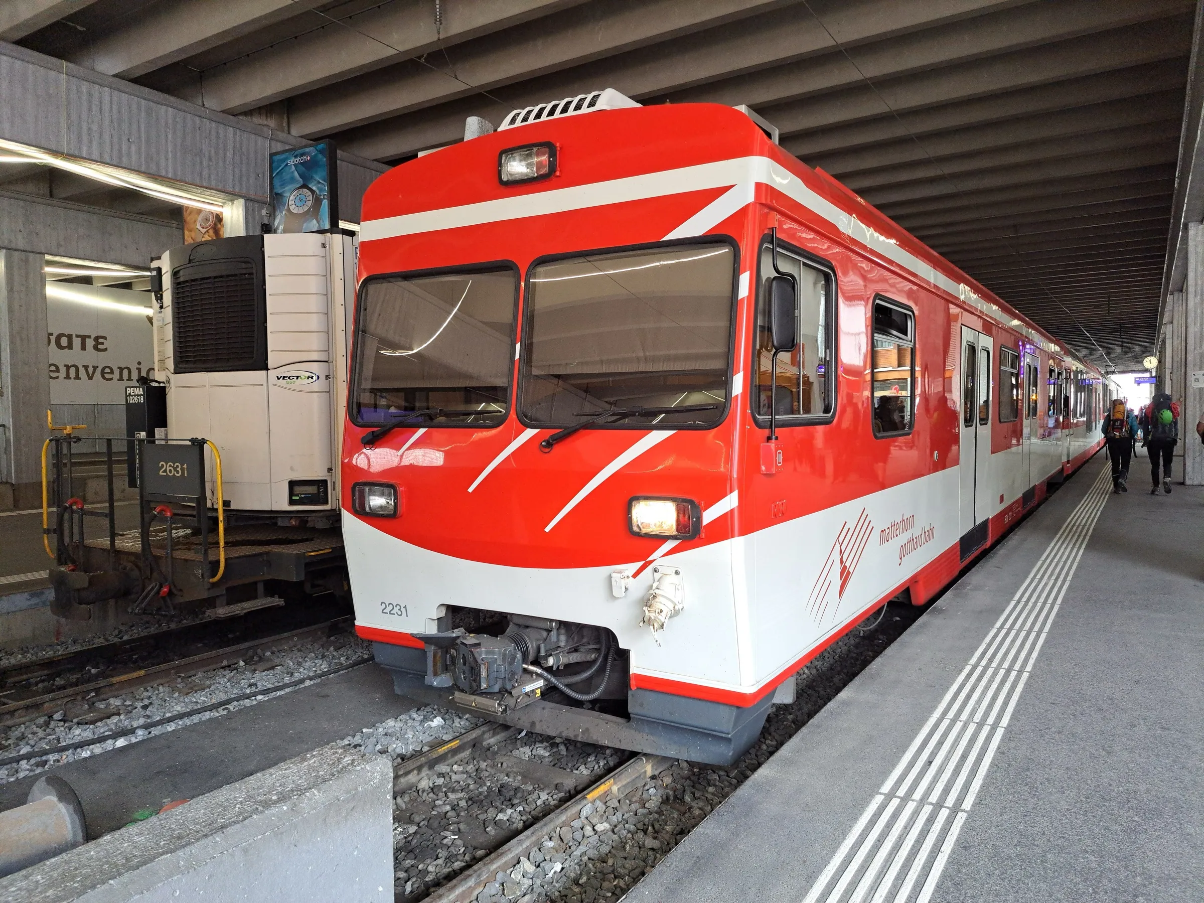 A red and white Matterhorn Gotthard Bahn train at the platform inside Zermatt station.